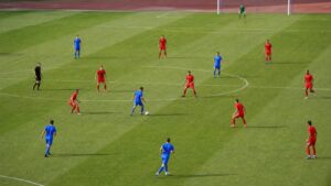 Two soccer teams in contrasting plain kits during a match showing possession against a compact defense