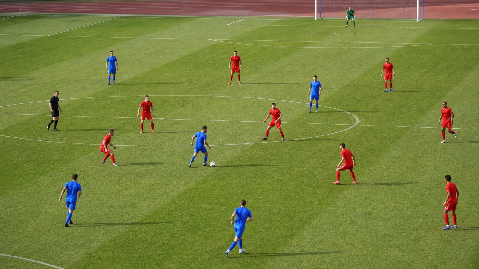 Two soccer teams in contrasting plain kits during a match showing possession against a compact defense
