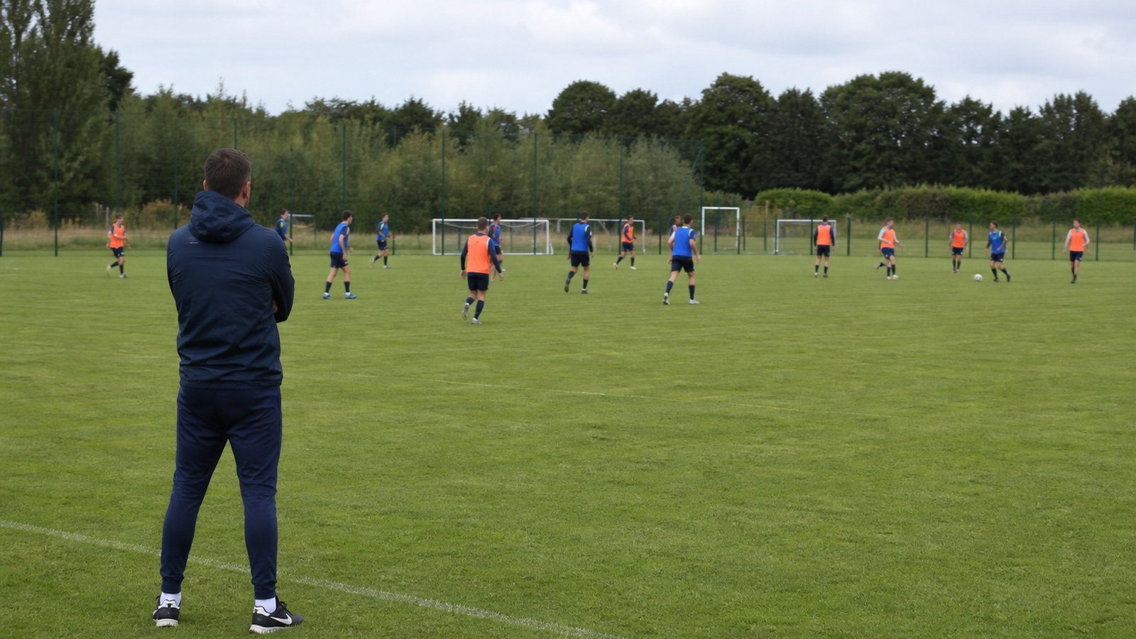 Soccer coach watching players adjust shape during an opponent simulation drill