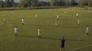 Soccer players arranged across a grass field in a clear team shape during practice