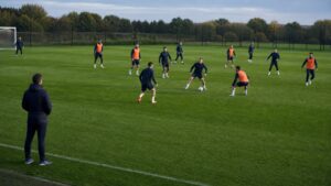 Soccer coach observing a balanced training drill with players spaced across the pitch